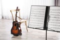 Note stand with music sheets and blurred acoustic guitar on background. Royalty Free Stock Photo