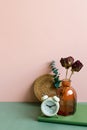 Notebook, alarm clock, vase of dry flower on green desk. pink wall background Royalty Free Stock Photo