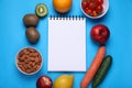 Notebook, almonds, fresh fruits and vegetables on light blue background, flat lay. Low glycemic index diet Royalty Free Stock Photo