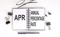 Notebook with APR Annual Percentage Rate on table with office tools