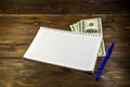 Notebook with ballpoint pen and dollar banknotes on the wooden desk Royalty Free Stock Photo