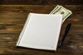 Notebook with ballpoint pen and dollar banknotes on the wooden desk Royalty Free Stock Photo