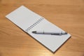 A notebook and ballpoint pen lying on a wooden table