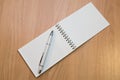 A notebook and ballpoint pen lying on a wooden table