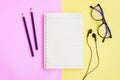Notebook,Black pencil,Eyeglasses and Black Wired Earphones  on pink and yellow background Royalty Free Stock Photo
