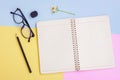 Notebook ,Black pencil,Eyeglasses,Eraser and White Flower on Pink,Yellow and Blue Background Royalty Free Stock Photo