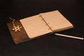 Notebook with blank brown sheets in a wooden cover, pencil and wooden snowflake on black background. Mockup. Top view Royalty Free Stock Photo