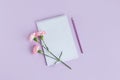 Notebook with blank page, pencil and Carnation flower on a violet pastel background Royalty Free Stock Photo