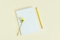 Notebook with blank page, pencil and Carnation flower on a yellow pastel background Royalty Free Stock Photo