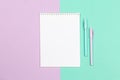 Notebook with blank page and two pens on a violet and turquoise background