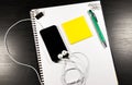 Notebook with blank paper, color sticky notes, pen, smartphone and clips on a wooden table Royalty Free Stock Photo