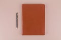 A notebook in a brown leather cover lies with a pen on the office table Royalty Free Stock Photo