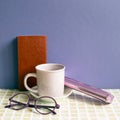 Notebook and coffee cup, glasses, pencil case on desk. purple wall background Royalty Free Stock Photo