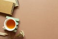 Notebook, colored pencil, dry flower, tea cup on brown background Royalty Free Stock Photo