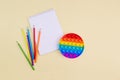 A notebook with colored pencils and pop it, trendy popular rainbow anti stress toy