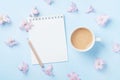 Notebook, cup of coffee and pink flowers on blue pastel background top view. Fashion woman working desk. Spring do list. Flat lay. Royalty Free Stock Photo