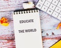 Notebook displays the phrase educate the world alongside crumpled paper, emphasizing the importance of business and