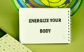 A notebook displays the text ENERGIZE YOUR BODY. Beside it, a calculator sits on a green surface. A circular design is in the Royalty Free Stock Photo