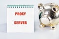 A notebook displays the words proxy server beside a shiny piggy bank, symbolizing financial security and technology