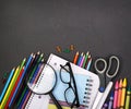 Notebook, exercise book, scissors and pencils on black board Royalty Free Stock Photo