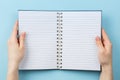 Notebook in female hands on blue background