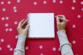 Notebook with female hands on Red Christmas background with snowflakes. Royalty Free Stock Photo