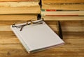 Notebook with fountain pen,glasses and books on wooden desk Royalty Free Stock Photo