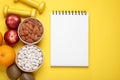 Notebook, fresh fruits and almonds on yellow background, flat lay. Low glycemic index diet Royalty Free Stock Photo