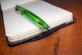 Notebook with green Ballpoint Pen for Sketching and Taking Quick Notes on a wooden Office Desk