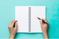 a notebook, a hand, and a pen set against a minimalist background.