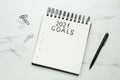 Notebook with inscription 2021 Goals, new year aims. Objects on white marble table, flat lay