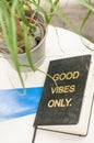 Notebook with inscription Good vibes only. Black notebook on a white table.