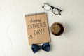 Notebook with inscription happy fathers day, blue bow tie, cup of coffee and glasses on white background, space for text Royalty Free Stock Photo