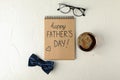 Notebook with inscription happy fathers day, blue bow tie, cup of coffee and glasses on white background Royalty Free Stock Photo