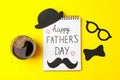 Notebook with inscription happy fathers day, cup of coffee, decorative bow tie, glasses, mustache and hat