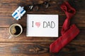 Notebook with inscription I love DAD, cup of coffee, glasses, gift box and tie on wooden background, space for text Royalty Free Stock Photo