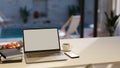 Notebook laptop and copy space on white tabletop house over blurred pool in background