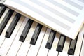 Notebook lies on black and white piano keys studying musical roughness of notes pianist music on synthesizer