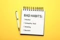 Notebook with list of bad habits and pen on yellow background, top view. Change your lifestyle