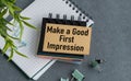 A notebook with a Make a Good First Impression sign on it. The notebook is on a table with a pair of scissors and a pair of paper. Royalty Free Stock Photo