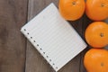 Notebook and Mandarin oranges placed on the old wooden floor.