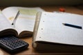 A notebook with math exercises written in pencil next to a calculator Royalty Free Stock Photo