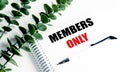 Notebook with members only text on white desk with pen and green leaves symbolizing exclusivity and restricted access Royalty Free Stock Photo
