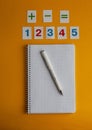 Notebook, numbers, white pen on a yellow background. Accessories for study. Mathematics, geometry, algebra