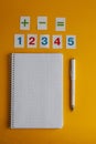 Notebook, numbers, white pen on a yellow background. Accessories for study. Mathematics, geometry, algebra