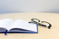 Notebook open with glasses on wooden table