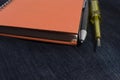 Notebook orange with pen and electric screwdriver check yellow placed on jeans. Royalty Free Stock Photo