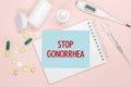 Notebook page with text Stop Gonorrhea on a table, pills and syringe. Medical concept