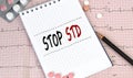 Notebook page with words - STOP STD Sexually transmitted diseases nearby with a pills and pencil, medical concept