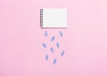 Notebook and paper clips on pink table looks like cloud and rain.